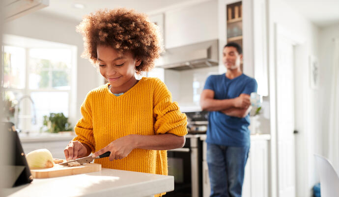 child cutting food with adult supervision